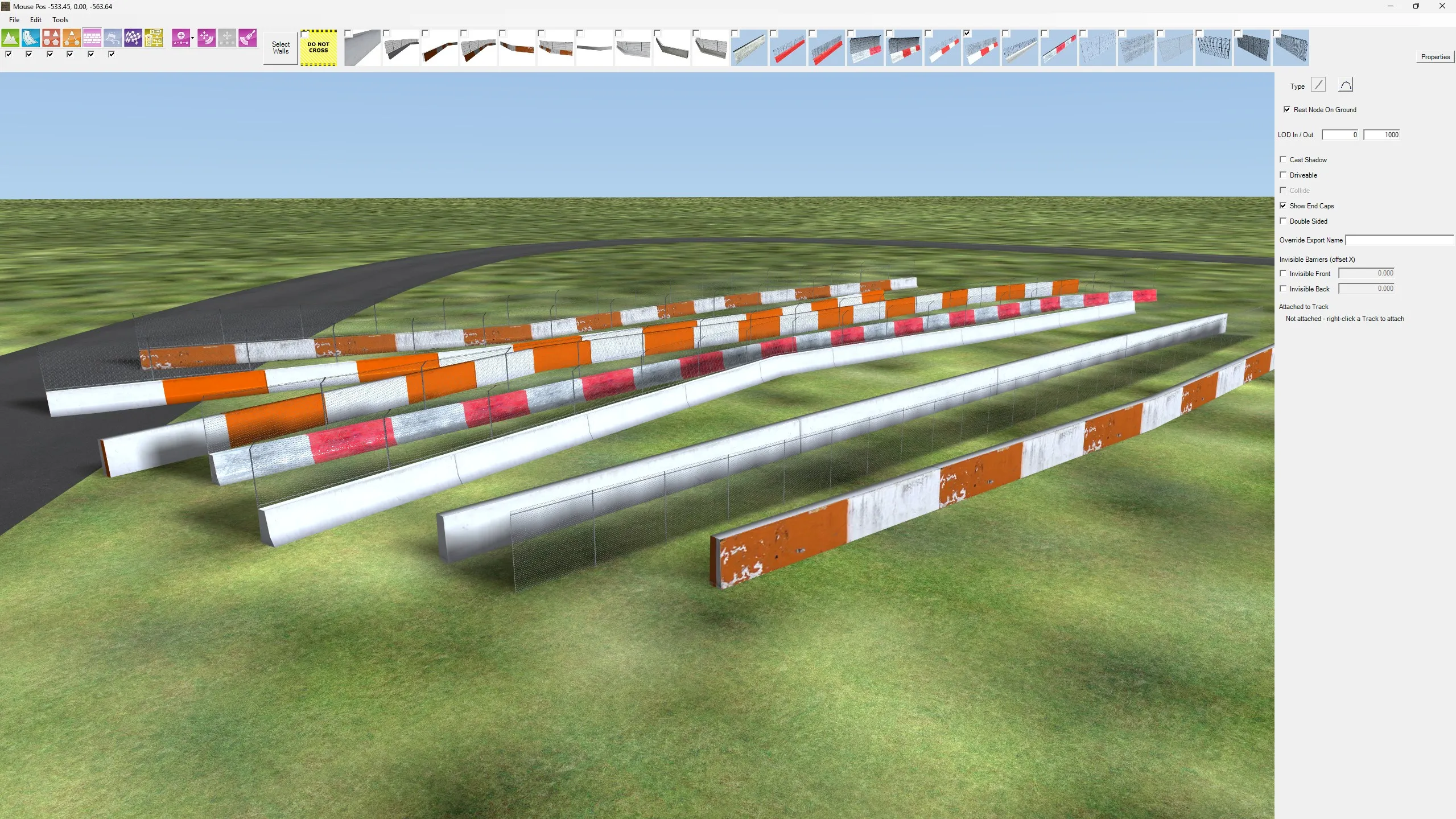 Concrete barriers, painted walls and catch fencing following the terrain beside a track